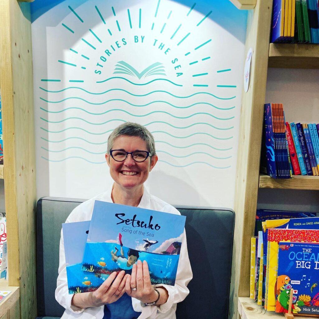 Children's author Fiona Barker holding copies of Setsuko and the Song of the Sea