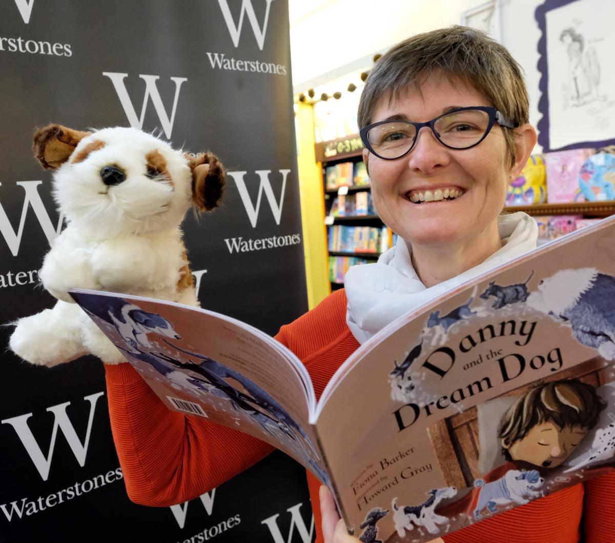 Author Fiona Barker reads a copy of Danny and the Dream Dog